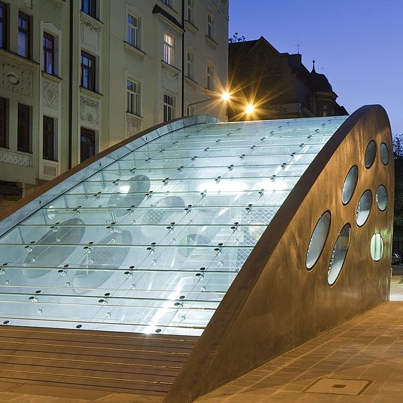 U-Bahn-Aufgang mit Glasdach und runden Öffnungen am Abend